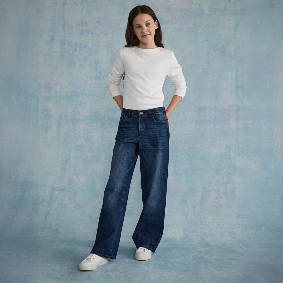 Biela, textúrovaná vrchná časť skombinovaná so širokými džínsami a bielymi teniskami.