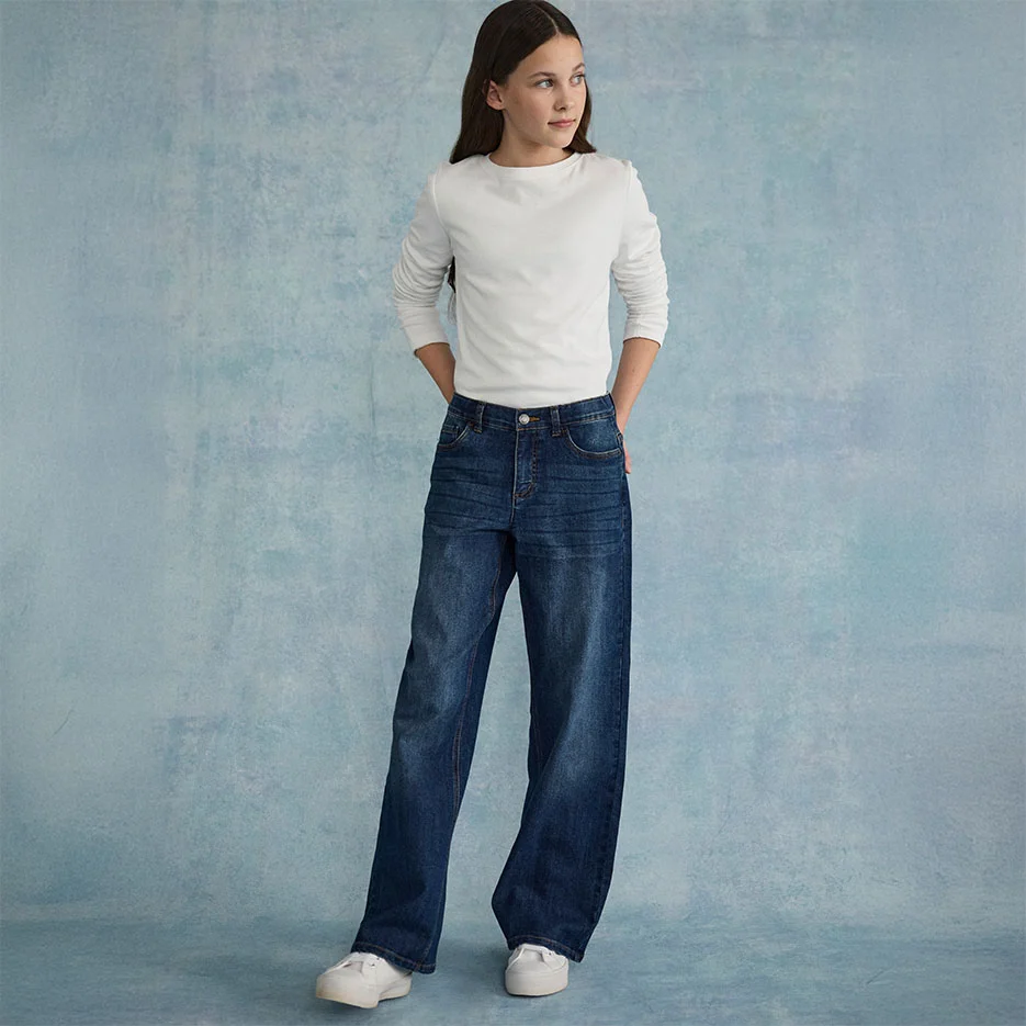 Biela, textúrovaná vrchná časť skombinovaná so širokými džínsami a bielymi teniskami.