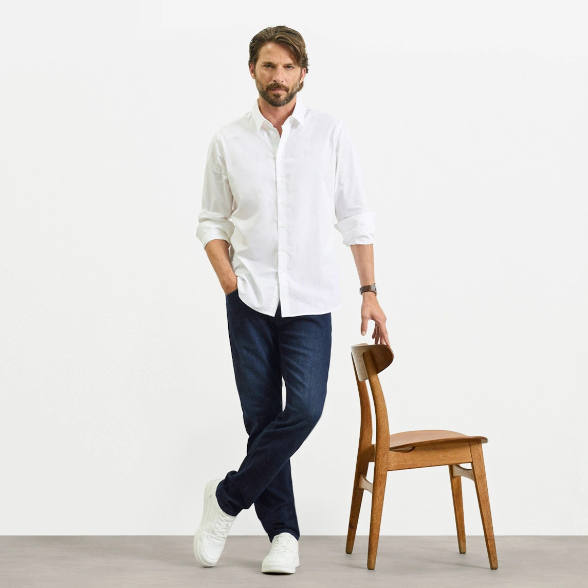 Biela košeľa, tmavé džínsy strihu Slim Fit a biele tenisky.