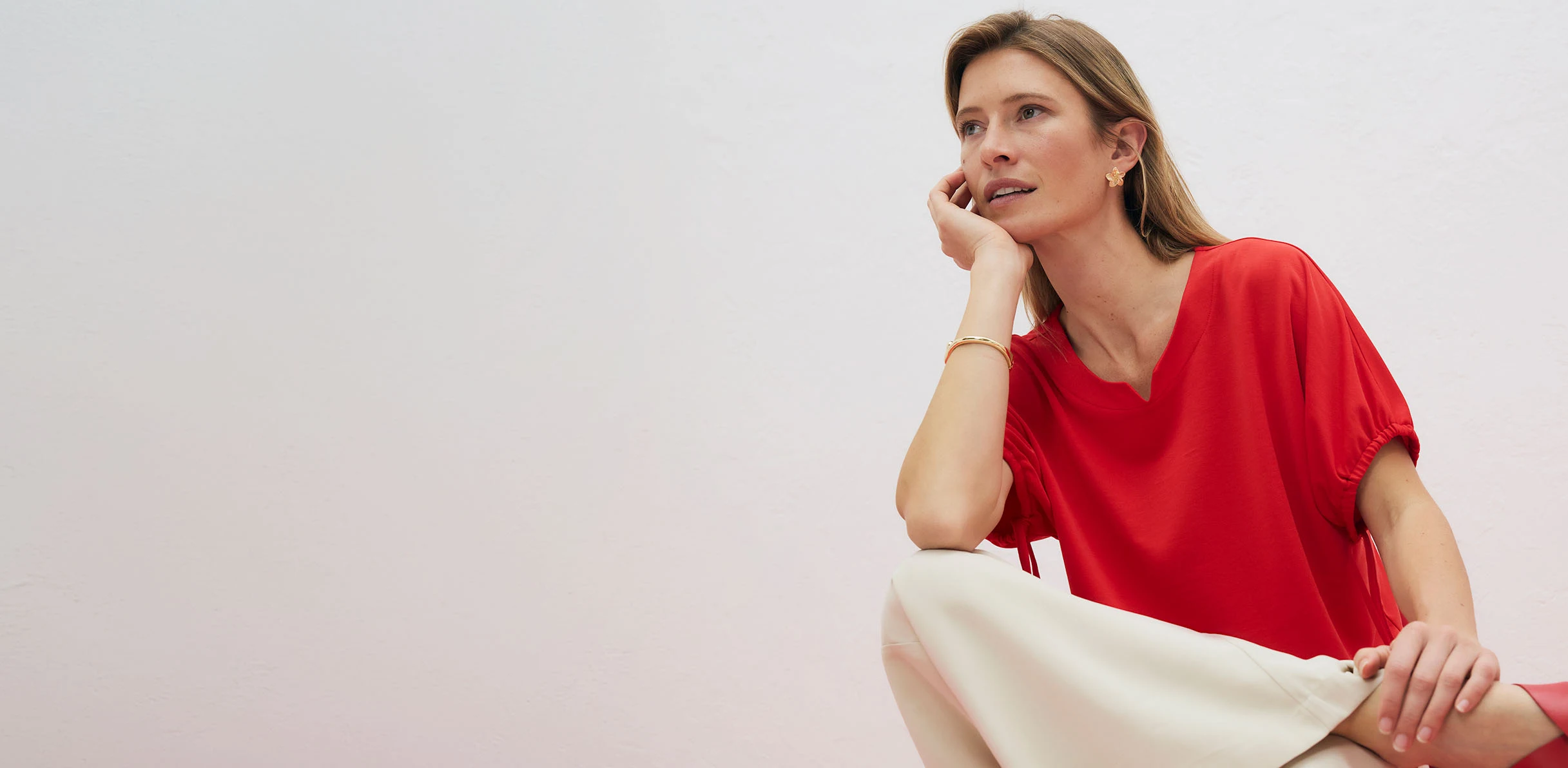 Elegantné červené tričko s výstrihom do V, kombinované so svetlými nohavicami.