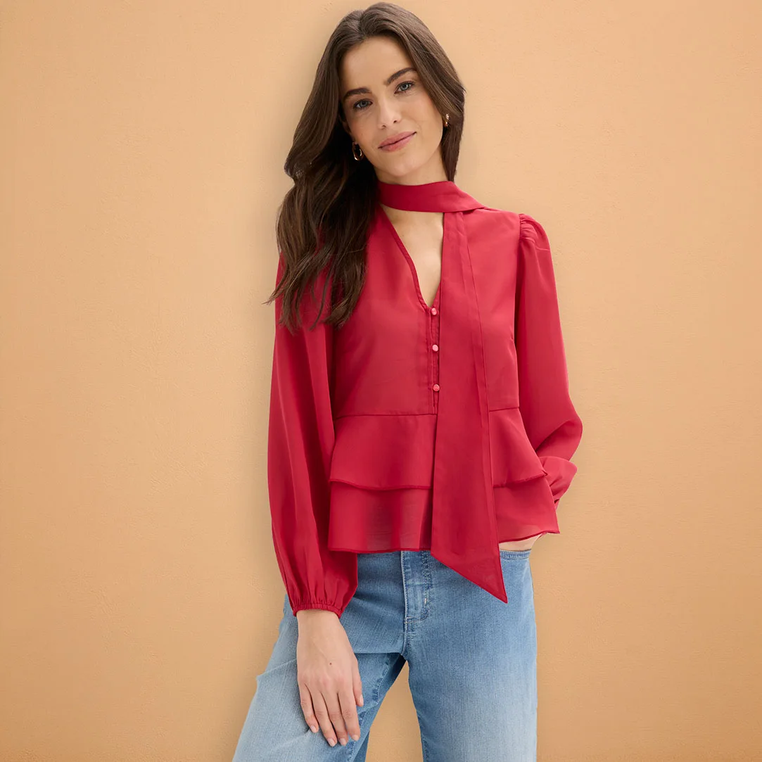 Červená blúzka s dlhým rukávom kombinovaná so svetlomodrými džínsami.